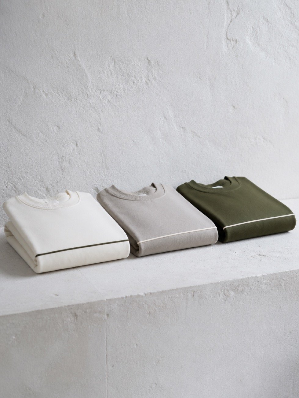 Three folded Kinesis sweatshirts arranged as a colourway lineup on a pale surface.