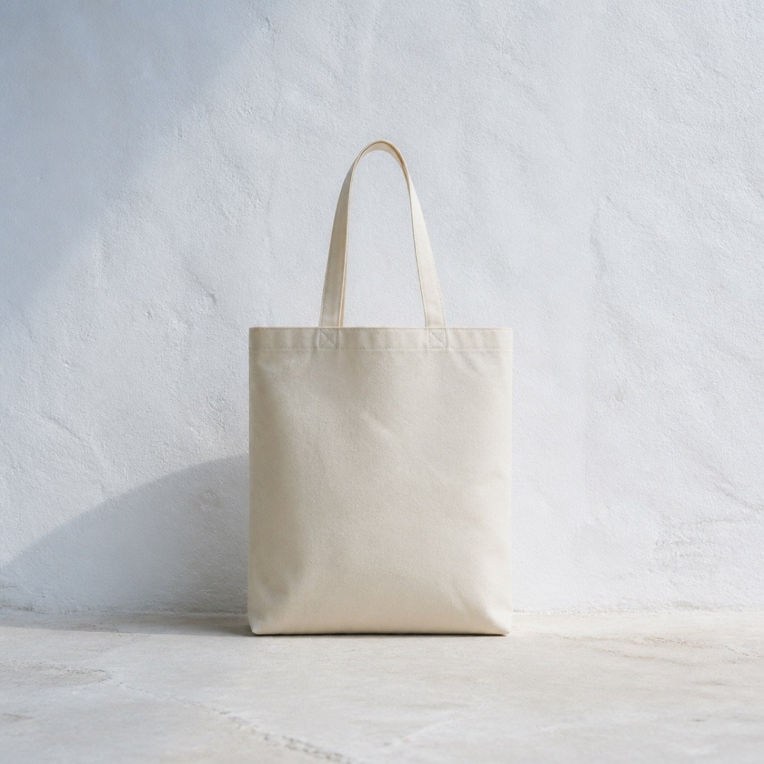 A natural canvas Kinesis tote bag photographed on stone in cool daylight.